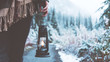 Woman traveling among snowy forest with kerosene lamp. Close-up. Wearing poncho. Winter is coming. Wanderlust and boho style