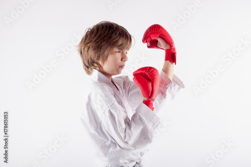 Zdjęcie XXL Młody chłopak sobie karate kimono i hodowane rękawice bokserskie koncentrując