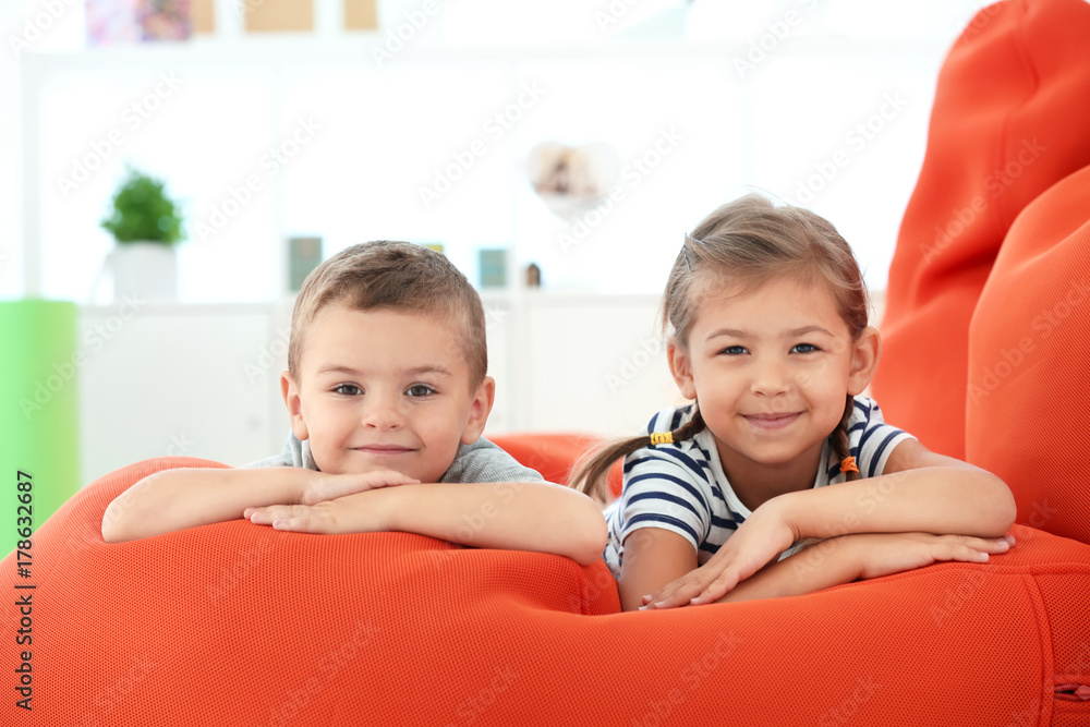 Cute boy and girl lying on bean bag cushion indoor