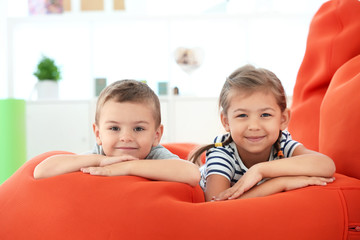 Canvas Print - Cute boy and girl lying on bean bag cushion indoor