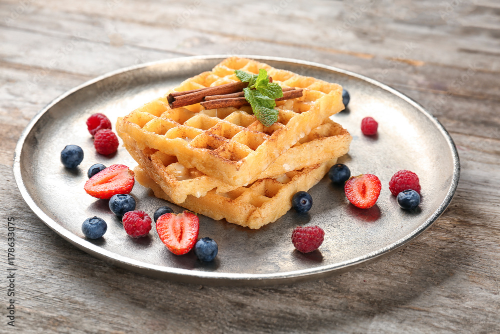Delicious cinnamon waffles with berries on metal tray