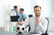 © Africa Studio - Young handsome man with soccer ball in office