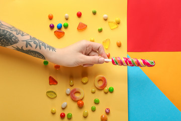 Sticker - Woman holding tasty lollipop on color background