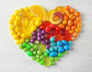 Wall Mural - Colorful candies arranged as heart on light background