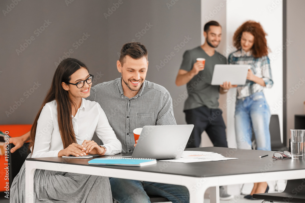 Young professionals working at table in office