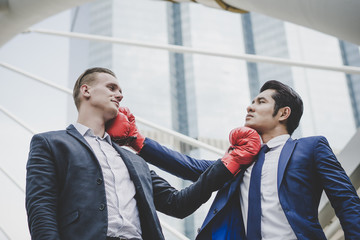 Businessman with red boxing gloves ready to fight his coworker.