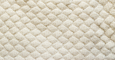 White knitted carpet closeup. Textile texture off white background. Detailed warm yarn background. Knit cashmere beige wool. Natural woolen fabric, sweater fragment.