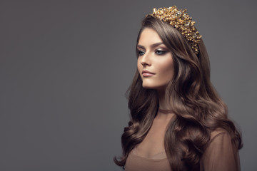 Beautiful woman in gold crown on her head. Long wavy brown hair.