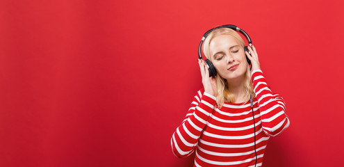 Wall Mural - Happy young woman with headphones on a solid background