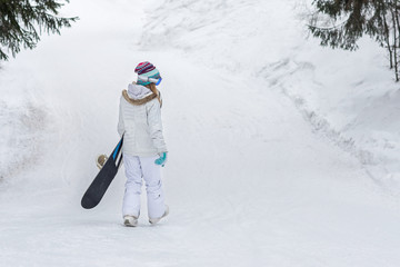 Wall Mural - Young girl snowboarder going down on a snowy mountain in the forest