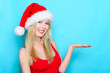 Blond woman presenting with hand. Christmas Santa hat.