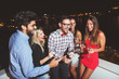 © Tijana - Group of people having a party on the roof, opening a champagne bottle