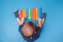 Bird Eye View Of Cute Little Asian 18 Months / 1 Year Old Baby Boy Child Hold Sticks & Plays A Musical Instrument Colorful Wooden Toy Xylophone
