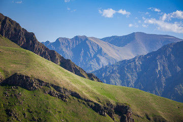 Wall Mural - Mountain range and green hill against blue sky. Nature landscape. Travel background. Holiday, hiking, sport, recreation. Exploring beauty world: beautiful outdoor scene in Svaneti, Georgia, Europe