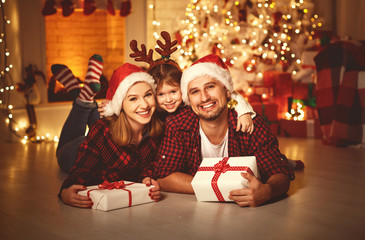 Merry Christmas! happy family mother father and child with magic gift near tree