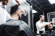 © nagaets - Young handsome barber making haircut of attractive man in barbershop