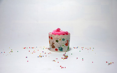 Wall Mural - One cup cake on the white background with colorful rounded sugar beads. cupcake is a small cake baked in a cup-shaped container.