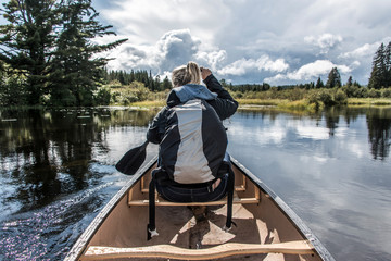 Girl canoeing with Canoe on the lake of two rivers in the algonquin national park in Ontario Canada on sunny cloudy day