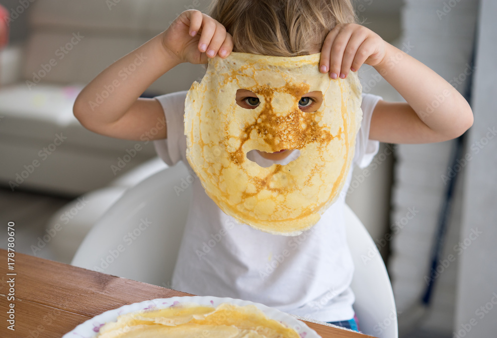 Little boy with a pancake instead of a mask on the face - obrazy, fototapety, plakaty 