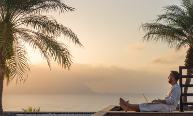 Young man with laptop at sunset