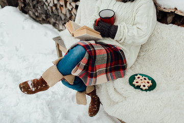 Cropped image of a woman enjoying reading a book on a cold winter day. Woman relaxing on a winter day.