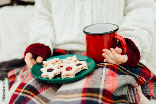 Plakat Cropped wizerunek kobieta trzyma talerza Bożenarodzeniowi ciastka i filiżanka herbata. Kobieta cieszy się jej bożych narodzeń ciastka i napój na zimnym zima dniu.