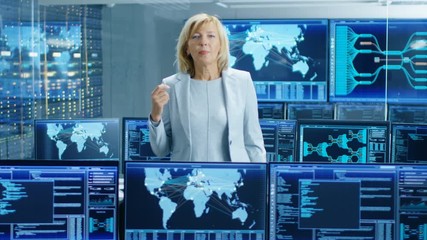 Fototapete - In the System Control Room Female Chief Engineer Describes Her Project Talking into the Camera. In the Background Multiple Screens Showing Interactive Data. Shot on RED EPIC-W 8K Helium Cinema Camera.
