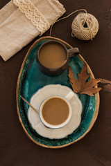 2 cups of coffee on turquoise ceramic tray with autumn leave