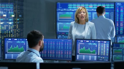 Poster - In the Stock Market Selling/ Buying Department Female Manager Talks with Male Trader. In the Background People Working, Screens Show Ticker Numbers and Graphs. 