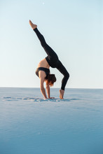 Young Woman Practicing Inversion Balancing Yoga Pose Handstand On Sand.