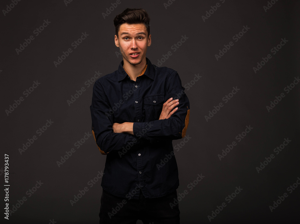 Young surprised man portrait of a confident businessman on a black background. Ideal for banners, registration forms, presentation, landings, presenting concept. - obrazy, fototapety, plakaty 