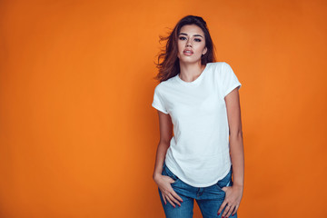 Sexy woman in a white T-shirt on the orange background. Mock-up.