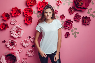 Sexy woman in a white t-shirt on a pink background with flowers.