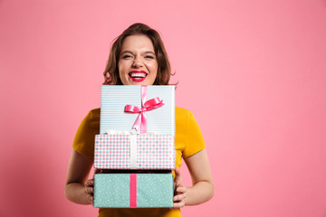 Poster - Happy laughing woman with red lips holding bunch of gift boxes, looking at camera