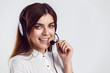 © proimagecontent - Cheerful brunette woman, kindly callcenter operator, wear black white shirt and black headphone set, smiling before white isolated background