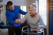 © WavebreakMediaMicro - Physiotherapist assisting patient to walk with walking frame