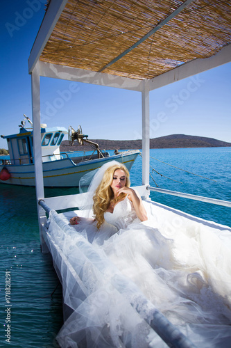 Fotografie, Obraz Beautiful blond woman with long legs in a white ball gown wedding dress it is ly