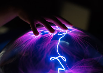 woman's hand touching plasma globe.