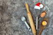Accessories for New Year's Christmas buns whisk in a santa hat, rolling pin, spoon and eggs, holiday concept on a light marble background with copy space view from above