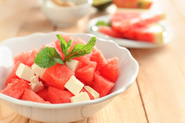 Wall Mural - Bowl of fresh salad with watermelon on table, closeup