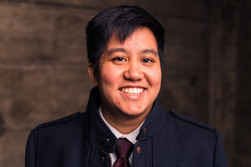 Young transgender man in formal clothing poses in a grungy urban location