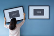 © eggeeggjiew - New year concept. Asian woman holding a picture frame of 2018 on blue wall.