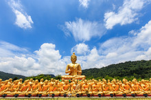 Big Golden Buddha Statue And Many Small Golden Buddha Statues Sitting In Row At At Buddha Memorial Park, Nakornnayok Thailand.