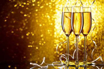 Three wine glasses with sparkling champagne with white ribbons on yellow background