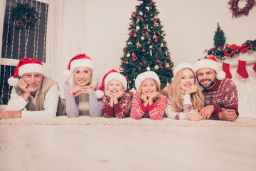 Wall Mural - Group of six cheerful beautiful relatives bonding hug embrace on carpet, married couples, excited siblings, grandad, granny, in knitted cute traditional x mas costumes, pine firtree, home, stockings