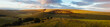 An English countryside panorama at sunset centred around a fenced opening.