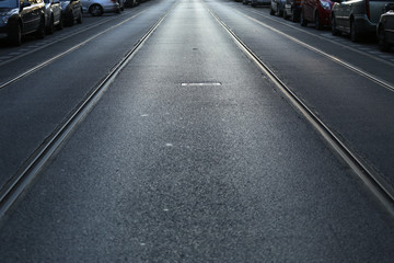 Asphalt road with tram tracks and parked cars