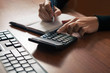 © Ruslan Ivantsov - the girl writes in a notepad, reading on the calculator on the wooden desktop with the keypad from the computer