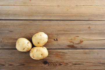 Wall Mural - Three young tuber raw white potatoes on rustic wooden background