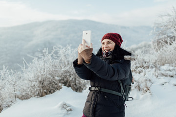 Smiling woman dressed warm taking a selfie during a winter walk